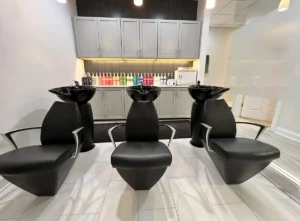- Ibi David Salon in Westlake, OH Three black salon washing chairs are positioned in front of sinks, with shelves of colorful hair products and gray cabinets in the background. - Ibi David Salon in Westlake, OH