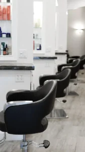 - Ibi David Salon in Westlake, OH A row of empty black salon chairs lined up in front of white counters with shelves holding hair products in a modern, well-lit salon. - Ibi David Salon in Westlake, OH