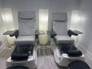 - Ibi David Salon in Westlake, OH Two modern pedicure chairs with foot baths and armrests are positioned side by side in a well-lit room with three tall floor lamps. - Ibi David Salon in Westlake, OH