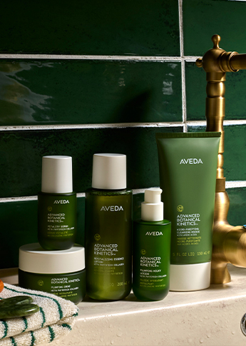 - Ibi David Salon in Westlake, OH Five Aveda Advanced Botanical Kinetics skincare products are arranged on a white sink, set against a green tile wall with a brass faucet. - Ibi David Salon in Westlake, OH